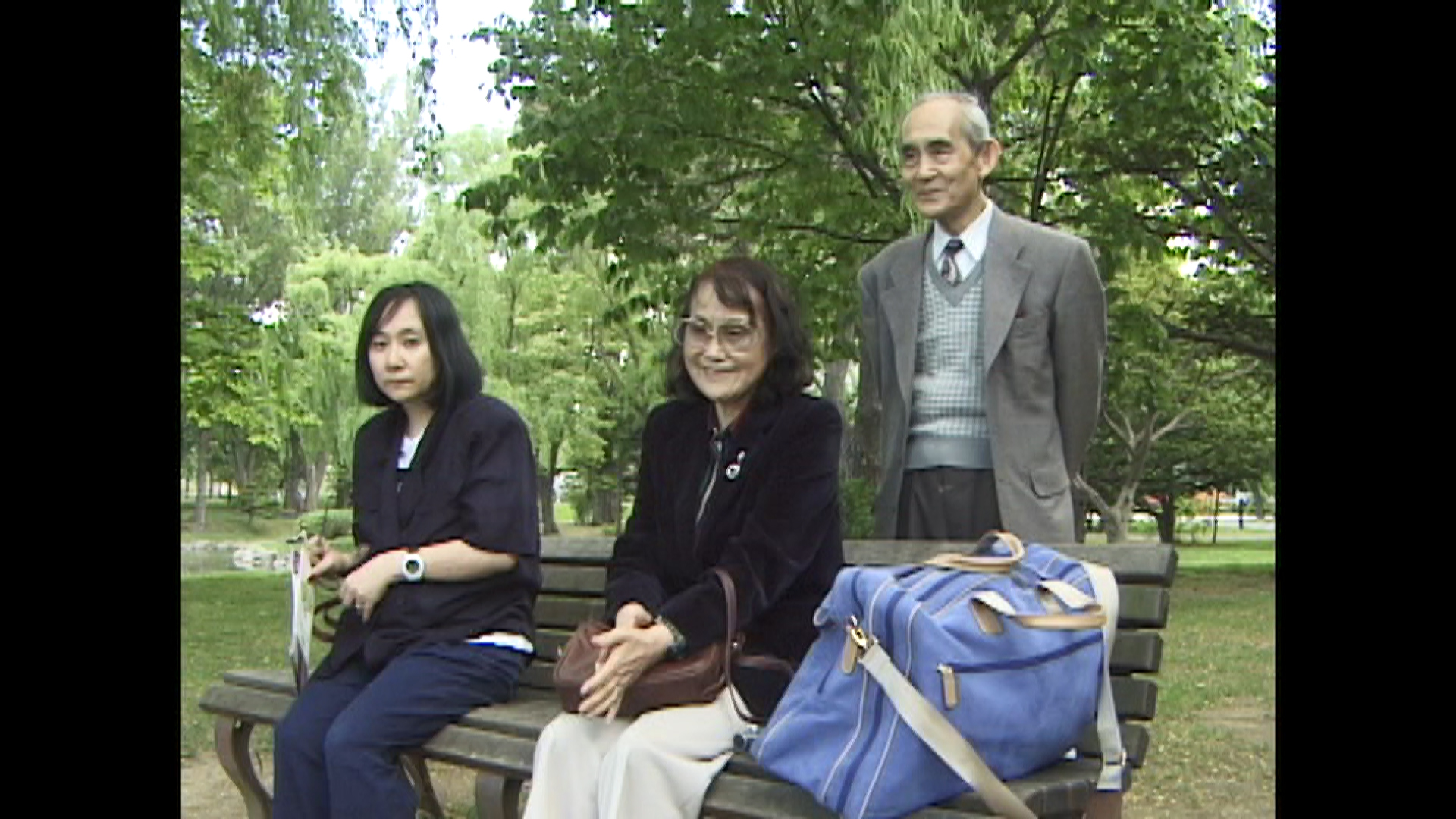 映画の場面写真。公園のベンチに並ぶ家族